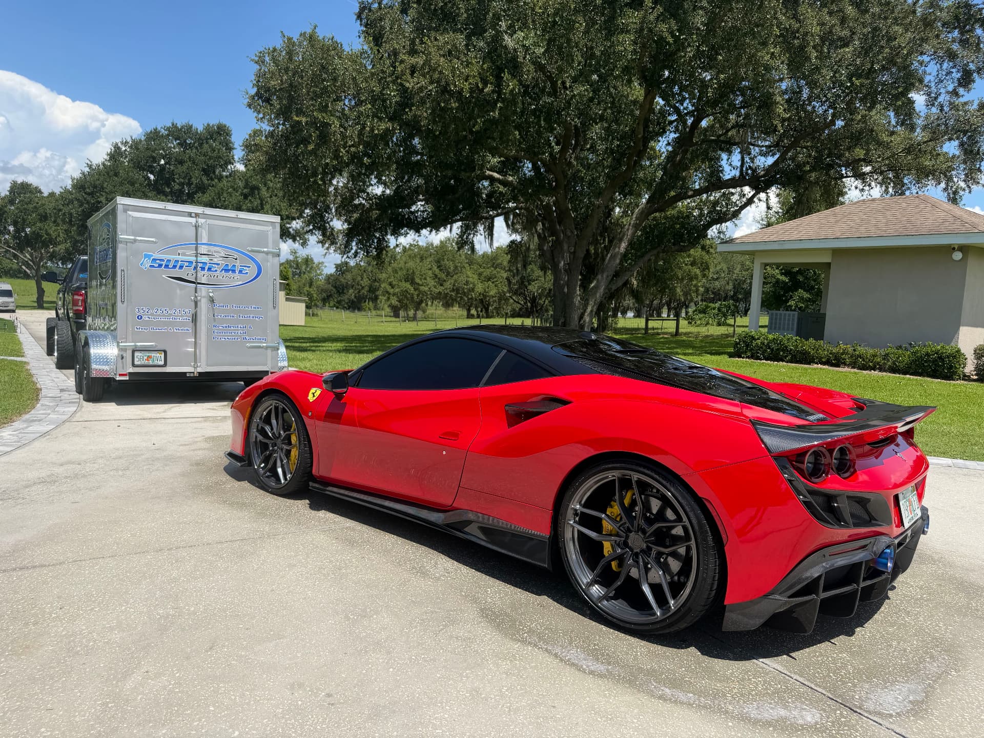 Red Ferrari F8 detailed by Supreme Detailing beside the company's mobile service trailer